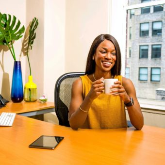 woman holding white ceramic mug at desk